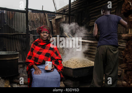 Ein Mann wird gesehen, Rösten sorghum Mischung, um den Alkohol in Kibera zu brauen. Für eine lange Zeit, die meisten Frauen aus Kibera Slums haben unter dem Einfluss von Alkohol. Nicht angesichts der Nebenwirkungen, Frauen hier ist aus verschiedenen Gründen einschließlich der Übernahme von Stress und über ihre Probleme in der Familie zu Hause zu vergessen. Dies ist wegen des Mangels an genügend Beschäftigungsmöglichkeiten und Unterstützung von ihren Ehemännern der hohe Alkoholkonsum hat zu einer höheren Rate von Todesfällen, Blindheit geführt, und das Risiko für viele gefährliche Krankheiten wie Krebs, Bluthochdruck, Schlaganfall und traumatischen Verletzungen wit Stockfoto