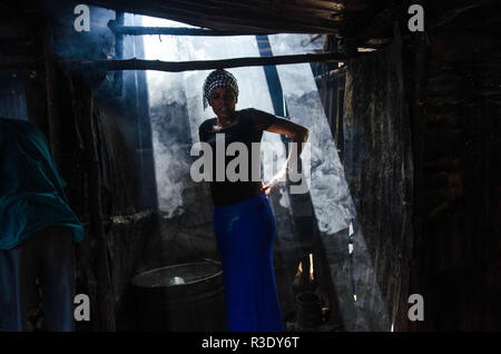 Eine Frau gesehen steht neben einem Eimer mit lokalen gebraut Alkohol in der Bar in Kibera. Für eine lange Zeit, die meisten Frauen aus Kibera Slums haben unter dem Einfluss von Alkohol. Nicht angesichts der Nebenwirkungen, Frauen hier ist aus verschiedenen Gründen einschließlich der Übernahme von Stress und über ihre Probleme in der Familie zu Hause zu vergessen. Dies ist wegen des Mangels an genügend Beschäftigungsmöglichkeiten und Unterstützung von ihren Ehemännern der hohe Alkoholkonsum hat zu einer höheren Rate von Todesfällen, Blindheit geführt, und das Risiko für viele gefährliche Krankheiten wie Krebs, Bluthochdruck, Schlaganfall und traumatischen Stockfoto