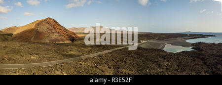 Luftaufnahme der Bermeja Berg von einer intensiv roten Farbe, von lavafeldern umgeben. Küstenstraße fließt durch einen kleinen See. Stockfoto