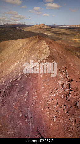 Luftaufnahme der Bermeja Berg von einer intensiv roten Farbe, von lavafeldern umgeben. Lanzarote, Kanarische Inseln, Spanien Stockfoto