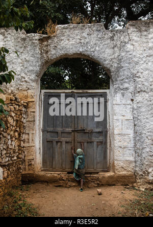 Mädchen, die versuchen, die riesige Tür eines muslimischen heiligen Ort, Harari Region, Harar, Äthiopien zu öffnen. Stockfoto