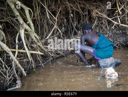 Suri Stamm Mädchen tun, Goldwaschen in einem Fluß, Omo Valley, Kibish, Äthiopien Stockfoto