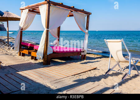 Holz- weg geht, durch sandige Strand, die komfortable Holz pergola mit weißen Vorhang Sunny Beach. Stockfoto