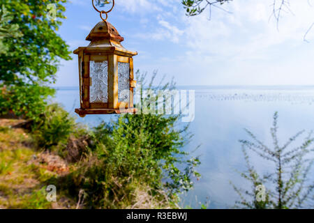 Laterne hängt am Baum hoch über dem offenen Meer. Stockfoto