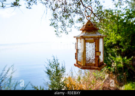 Laterne hängt am Baum hoch über dem offenen Meer. Stockfoto