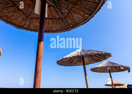 Strohgedeckten Sonnenschirm Schuß von unten über blauen Himmel. Mit Holz und Schilf Stockfoto