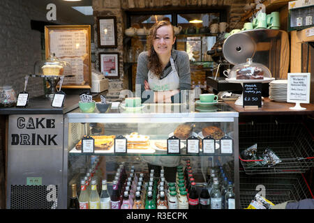 Eine lächelnde junge Frau Arbeiter mit Essen und Trinken in der Moderne alte Druckerei Cafe Restaurant in Llandovery Wales UK KATHY DEWITT Stockfoto