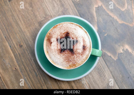 Festliche Tasse Cappuccino mit einem Christmas Star Design von Schokolade bestreut mit aufgeschäumter Milch in eine grüne Tasse und Untertasse UK KATHY DEWITT Stockfoto