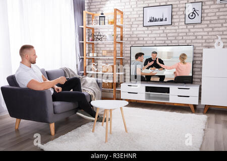 Mann sitzt auf einem Sofa Fernsehen zu Hause beobachten Stockfoto