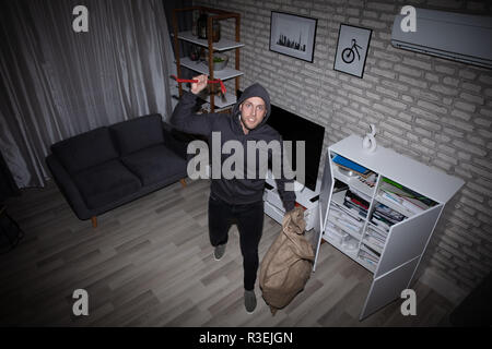 Porträt eines jungen männlichen Dieb mit der Brechstange und Sack stehend im Haus Stockfoto