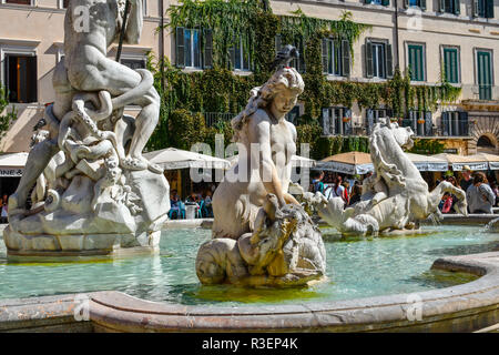 Eine taube sitzt auf einer Renaissance statue Kopf als Touristen genießen die Cafés Zusammenarbeit den Neptunbrunnen in der Piazza Navona in Rom, Italien. Stockfoto