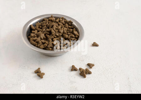 Trockennahrung für Katzen oder Hunde in einer Metallschüssel auf hellem Hintergrund mit Kopie Raum, ausgewählte konzentrieren, enge Tiefenschärfe Stockfoto