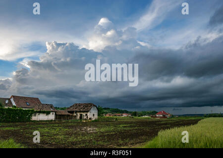 Sturmwolken sammeln sich über ländlichen Bauernhäusern und grünen Feldern im Mures-Tal, Transsilvanien, Rumänien; malerischer Landschaftsstil Stockfoto