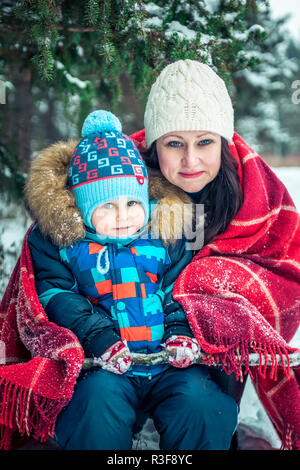 Frau mittleren Alters und ihr Sohn im Winter Wald Stockfoto