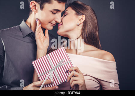 Man gibt ein Geschenk, um seine Freundin für Valentines Tag auf schwarzem Hintergrund. Stockfoto
