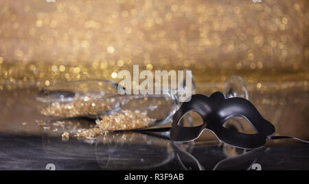 Karneval Party. Venezianische Maske schwarz und champagner Gläser auf goldenen bokeh Hintergrund, Reflexionen, Kopie Raum Stockfoto