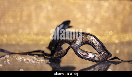 Karneval. Venezianische Maske mit Federn auf goldenen bokeh Hintergrund, Reflexionen, Kopie Raum Stockfoto