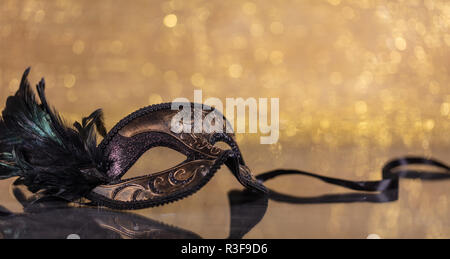 Karneval. Venezianische Maske mit Federn auf goldenen bokeh Hintergrund, Reflexionen, Kopie Raum Stockfoto