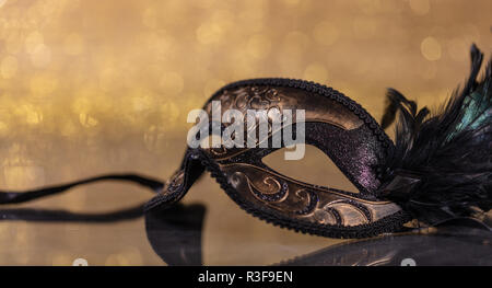 Karneval. Venezianische Maske mit Federn auf goldenen bokeh Hintergrund, Reflexionen, Kopie Raum Stockfoto