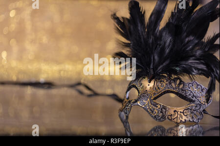 Karneval. Venezianische Maske mit Federn auf goldenen bokeh Hintergrund, Reflexionen, Kopie Raum Stockfoto