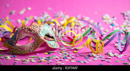 Karneval Party. Farbenfrohe Maske, Luftschlangen und Konfetti auf die hellen rosa Hintergrund, Banner Stockfoto