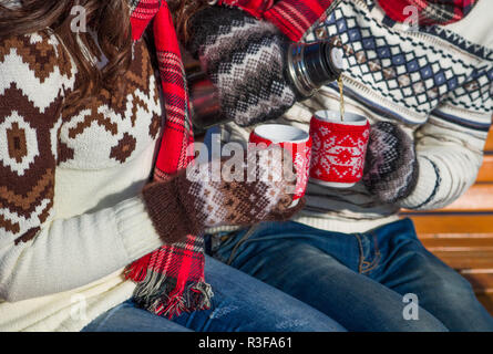 Junges Paar gießt heißen Tee aus der Thermoskanne im Winter Wald Stockfoto