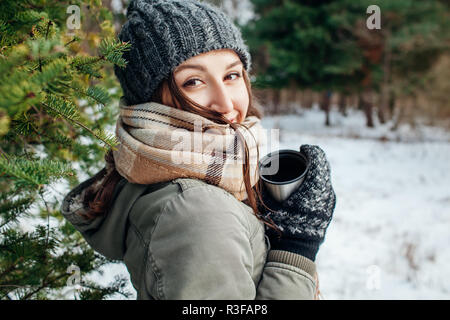 Junge Frau hält eine Thermoskanne und Getränke Tee im Herbst Wald Stockfoto