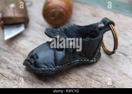 Bunte Leder Schlüsselanhänger in der Form des alten Schuh auf hölzernen Hintergrund Stockfoto