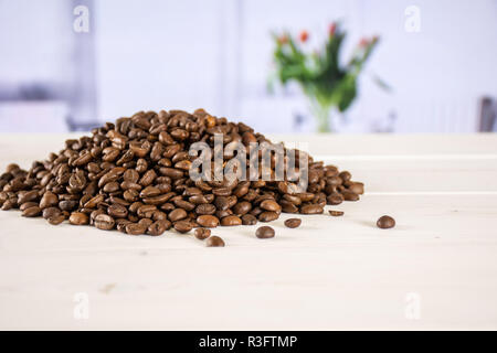 Menge ganze dunkle braune Bohnen süß Arabica mit roten Blumen auf Weiß im Hintergrund Stockfoto