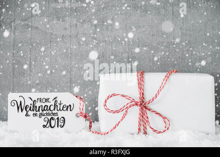 Etikett mit Deutschen Kalligraphie Frohe Weihnachten und ein Glueckliches 2019 bedeutet, frohe Weihnachten und einen guten Rutsch ins Jahr 2019. Eine weiße Geschenk mit roter Ribbn. Grung Stockfoto