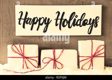 Mit englischen Kalligraphie Happy Holidays unterzeichnen. Drei weiße Geschenke mit roten Ribbn. Grunge Zement Hintergrund mit Schnee Stockfoto