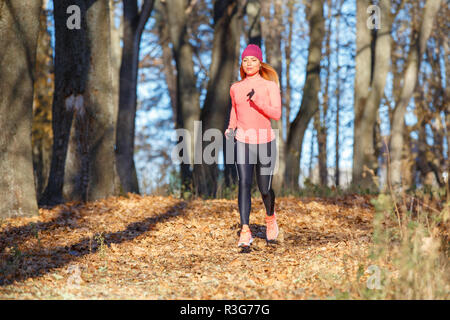 Junge fitness Frau Joggen im Herbst in der Morgen. Attraktives Mädchen auf den Weg in kaltem Wetter zu laufen. Gesunder Lebensstil Bild mit Kopie Raum Stockfoto