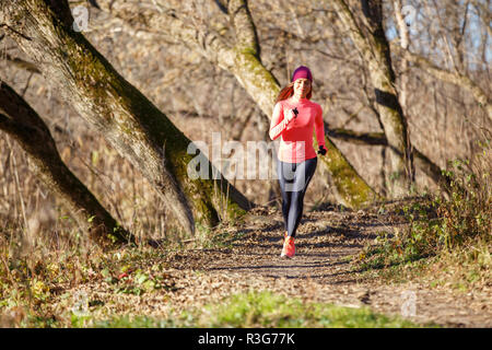 Junge fitness Frau Joggen im Herbst in der Morgen. Attraktives Mädchen auf den Weg in kaltem Wetter zu laufen. Gesunder Lebensstil Bild mit Kopie Raum Stockfoto