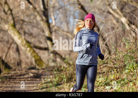 Junge fitness Frau Joggen im Herbst in der Morgen. Attraktives Mädchen auf den Weg in kaltem Wetter zu laufen. Gesunder Lebensstil Bild mit Kopie Raum Stockfoto