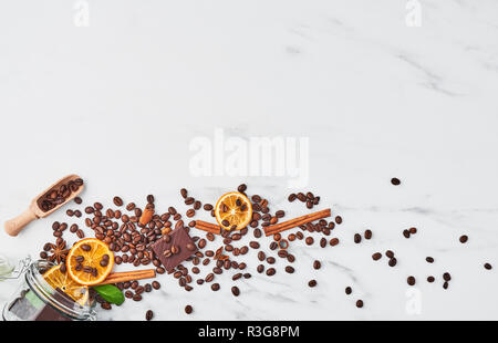 Kaffee im Glas Glas mit Bohnen, Schokolade, getrocknete Orangen, Anis und Zimtstangen auf weißem Hintergrund. Konzept der Kaffee mit verschiedenen Gewürzen Stockfoto