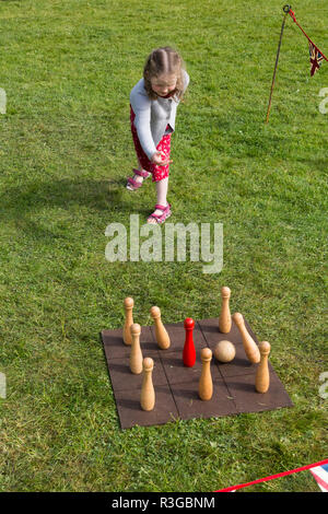 Ein sechs Jahre altes Mädchen spielen mit einem altmodischen traditionellen klassischen Satz von Kegeln auf einem Brett, das Werfen einer Kugel, die von den Spielern. Das VEREINIGTE KÖNIGREICH (98) Stockfoto