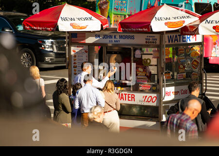 NEW YORK CITY - USA - 02.November 2017. Einige Touristen kaufen Hot Dogs von einem Kiosk im Times Square. Stockfoto