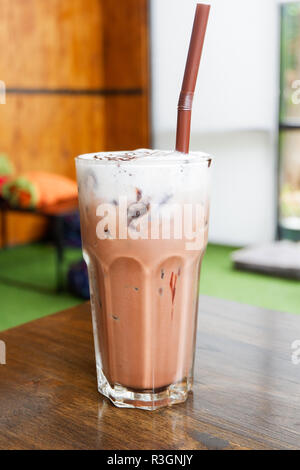 Iced cocoa/Glas eisgekühlten Kakao trinken und Milchschaum creme Schaum - Eistee Schokolade Kakao Glas und Stroh auf dem Tisch im Café Stockfoto