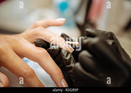 Professionelle Nagel Künstler mit schwarzen Handschuhe färben Nägel von Client Stockfoto