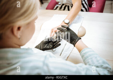 Ansicht von oben Nagel Künstler in schwarz Handschuhe, Maniküre für Frau Stockfoto