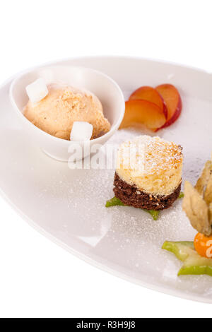 Brownie Chocolate Brownie mit Eis und Pflaumen serviert auf einem Telle Stockfoto