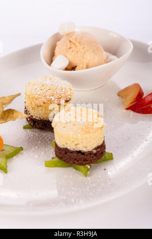 Brownie Chocolate Brownie mit Eis und Pflaumen serviert auf einem Telle Stockfoto