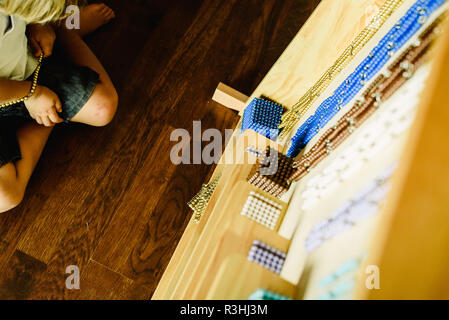 Händen eines Kindes Manipulation von pädagogischen Materialien zu lernen in einer Montessori Schule zu zählen. Stockfoto