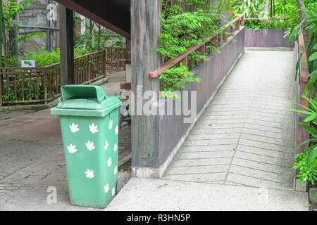 Grünen Kunststoffbehälter oder Papierkorb in der Nähe der Weg in den Zoo Park Stockfoto