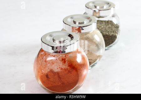 Glas Gewürzdosen mit Cayenne Pfeffer, Kardamom und Majoran Stockfoto