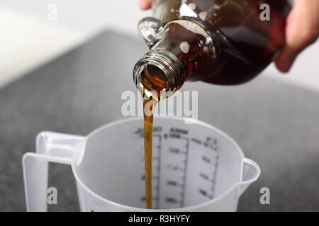 Gießen Ahornsirup in Messbecher. Die Apfelwein Torte Serie. Stockfoto