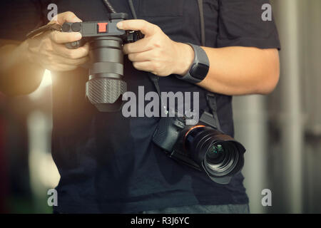 Fotografie Konzept. Nahaufnahme von professionellen Fotografen Kontrolle auf der Rückseite der Kameras. Vintage Farbton. Bild zum Text Nachricht hinzufügen. Backd Stockfoto
