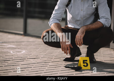 7/8-Ansicht der männlichen Detektiv sitzen in der Nähe der Beweise Stockfoto