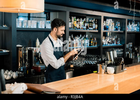 Barkeeper in Schürze und Tippen auf digital Tablet Stockfoto