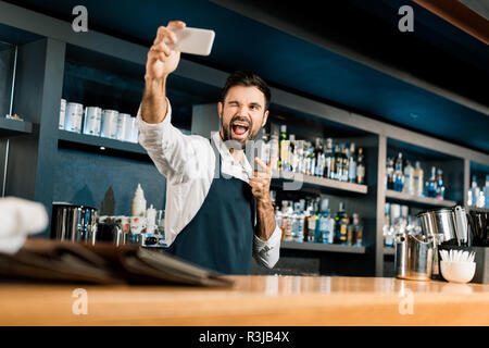 Barkeeper stehend mit Smartphone und unter selfie in bar Stockfoto